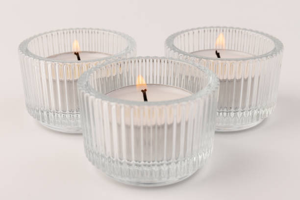 istock Burning tea candles in a glass holder, isolated on white. Space for text 1359935721