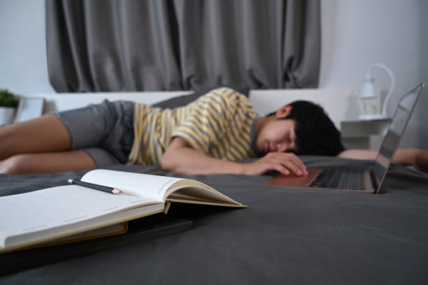 istock Tired asian man sleeping on bed with laptop. 1359941078