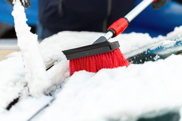istock Person with broom brushing snow from windshield in close-up 1359942435