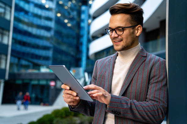 istock Happy young business man with tablet at work in modern urban background 1359951153