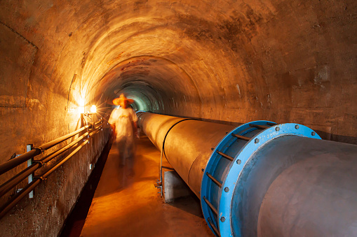 Horizontal water pipe or pipeline in a mountain tunnel. Irrigation system, agriculture, transportation concepts. Selective focus.