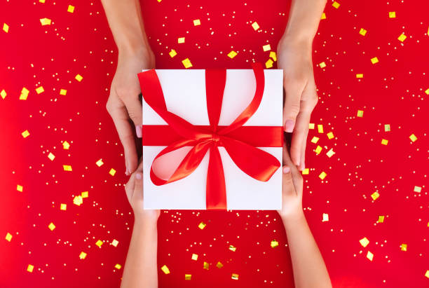 istock gift box in children's hands on a red background, presenting a gift, christmas background 1359953187