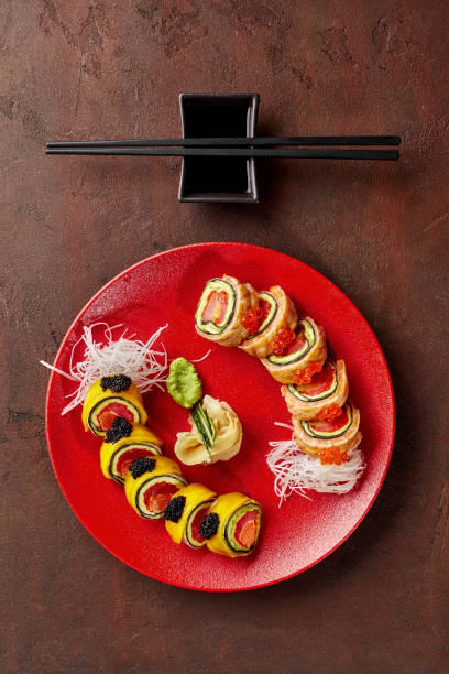 rolls with tuna, salmon, mango, avocado, caviar served on red plate on textured brown countertop - brown rice salmon rice mango imagens e fotografias de stock