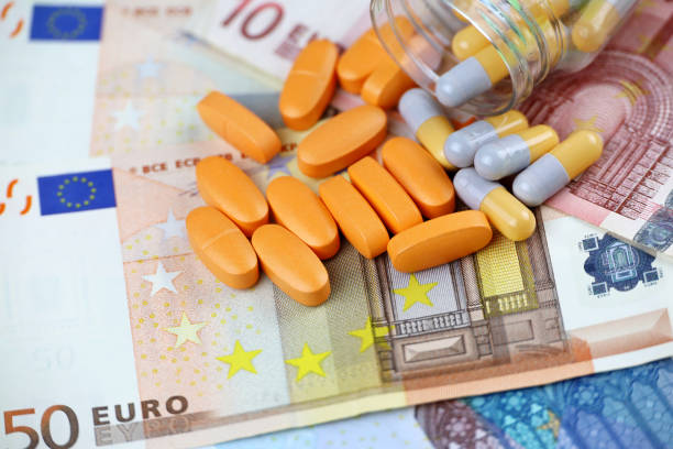 istock Pills and capsules scattered from a bottle on euro banknotes 1359954773