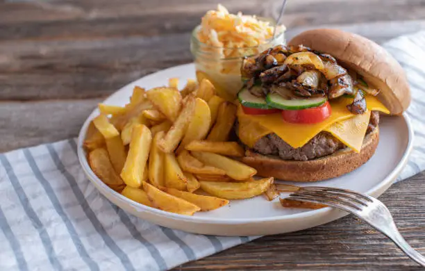 Homemade fresh cooked fast food meal with a delicious cheeseburger, french fries and coleslaw. Served isolated on wooden table with copy space