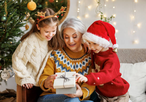 冬休み中に笑顔の祖母にクリスマスギフトボックスを与える小さな子供の孫娘と孫 - grandmother senior adult smiling women ストックフォトと画像