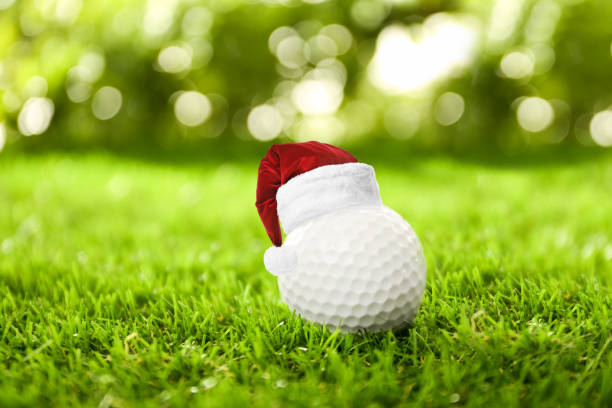 istock Golf ball with small Santa hat on green course 1359960749