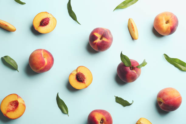 istock Fresh ripe peaches and green leaves on light blue background, flat lay 1359965271