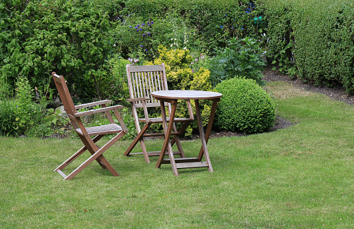 Wooden chairs and a table in the garden on the lawn