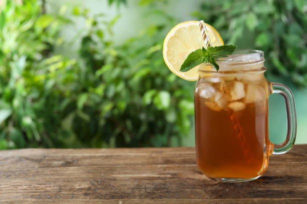 Delicious iced tea in mason jar on wooden table outdoors, space for text Delicious iced tea in mason jar on wooden table outdoors, space for text iced tea stock pictures, royalty-free photos & images