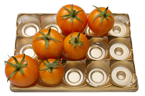 six orange tomatoes lie on a gold tray with cells, the cells are not completely filled, concept, on a white background