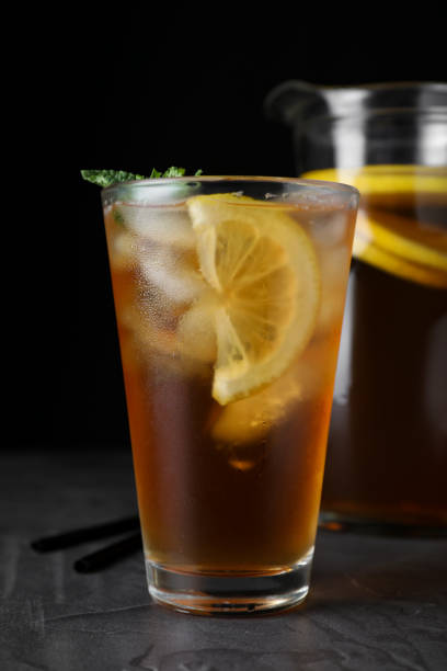 istock Delicious iced tea on grey table against black background, closeup 1359968763