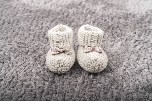 istock Small baby booties with a bow on the carpet. 1359969362