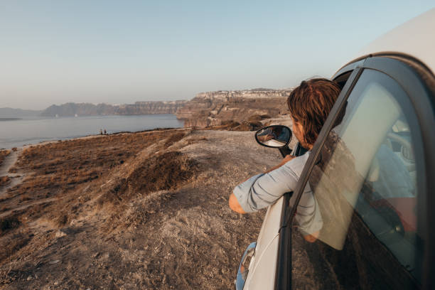 istock Young man driving car at sunset, road trip concept 1359970781