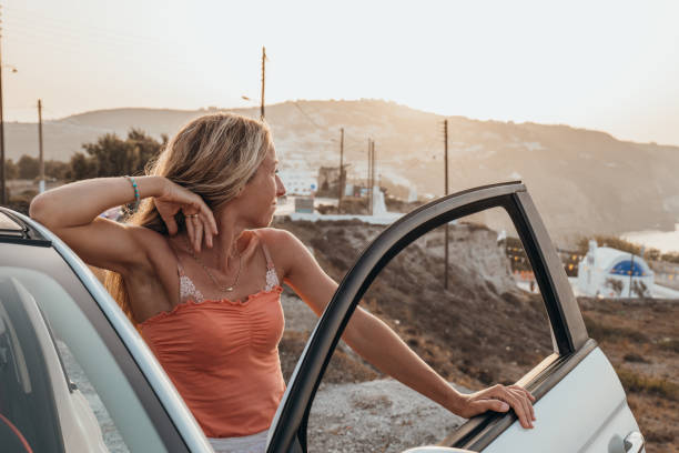 jeune femme dans sa voiture décapotable regardant le littoral, concept de road trip - car door flash photos et images de collection