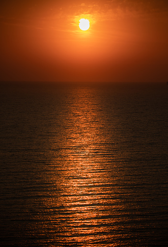 Bright red sunset over the sea and the beach, close-up. Thailand.