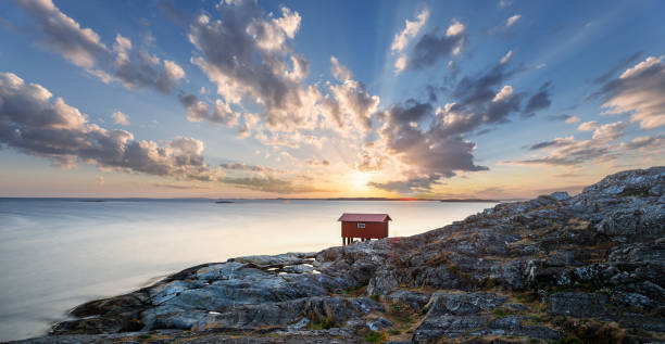 a colorful sunset of a red little fisherman's hut at the coast of sweden. Longe exposure stock photo