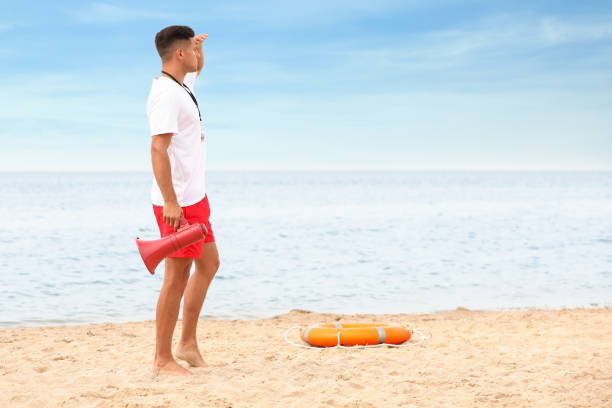 apuesto socorrista masculino con megáfono en la playa de arena - marine safety equipment audio fotografías e imágenes de stock