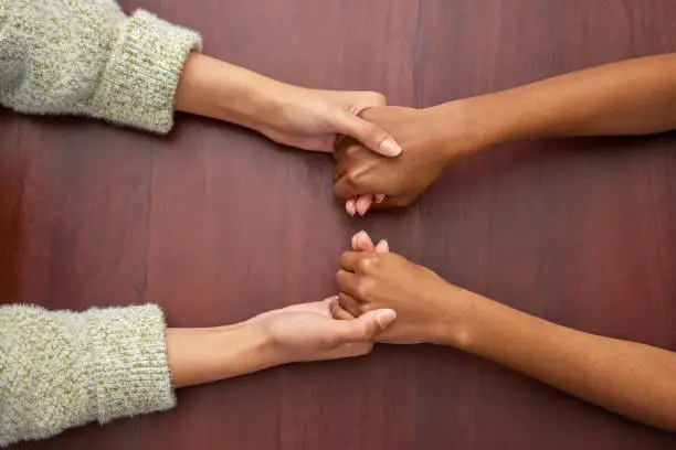 Photo of Shot of two unrecognizable women holding hands