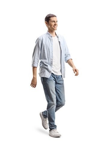 Full length shot of a happy young man in jeans and shirt walking isolated on white background