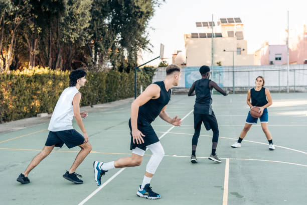 istock Four multicultural friends playing basketball outdoors 1359983274