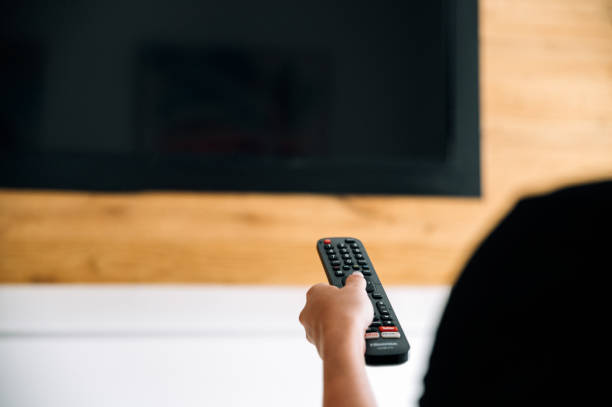 istock Unrecognizable woman turning on TV 1359984273