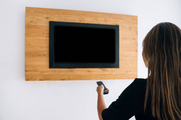 istock Unrecognizable woman turning on TV 1359984274