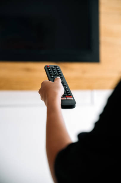 istock Unrecognizable woman turning on TV 1359984275
