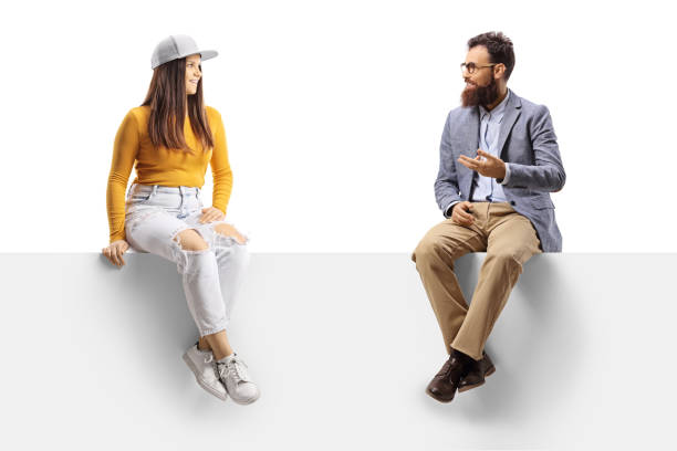 istock Bearder man talking to a young casual female seated on a blank panel 1359984293