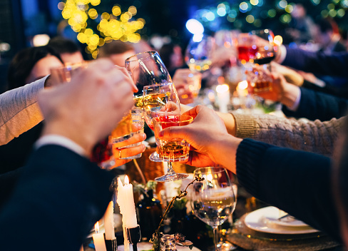 group of people with glasses raise a toast celebrate christmas celebrations against the background of colorful garlands