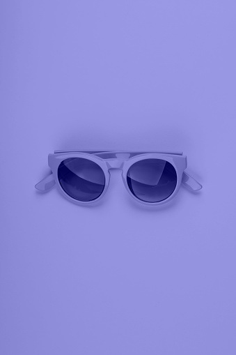 Purple very peri color sun glasses. Monochrome minimal fashion flat lay. Vertical