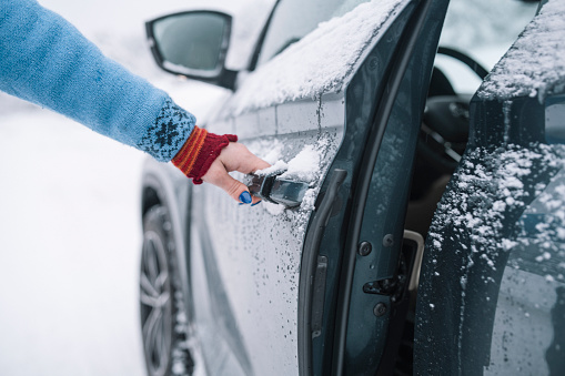Cropped hand of unrecognisable person opening a car door in winter