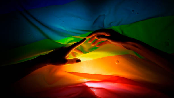 Hands dancing with shadows and light. Soft and shy touches. LGBT flag in background Hands dance on a rainbow background. Ephemeral shadows, LGBT symbols Myth: Crossdressing is Exclusive to LGBTQ  Individuals stock pictures, royalty-free photos & images