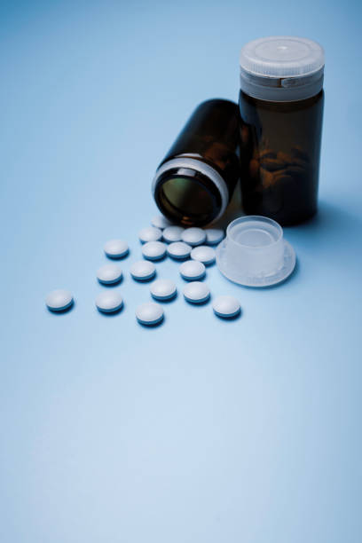 istock bottle with a small, blue painkiller pills on a blue background 1359986706