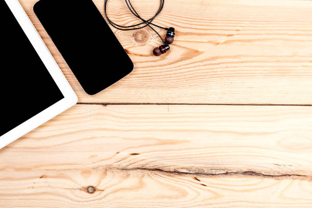 istock computer, smartphone and headphones on wooden table top view. background and workspace for writing text and advertising 1359989694