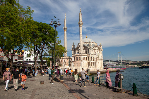 Historical Ortakoy(Mecidiye) mosque and Bosphorus view.People watching the sea.İstanbul,Turkey.20 May 2021