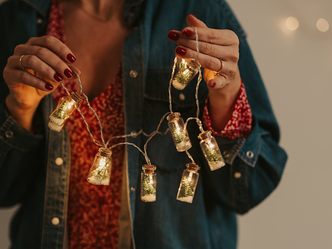 Woman holding christmas tree string lights in her hands nice atmosphere\nClose up of hands