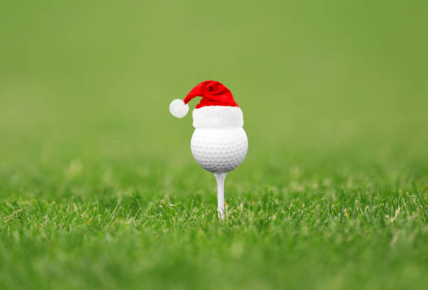 istock Golf ball with small Santa hat on tee at course 1359996460