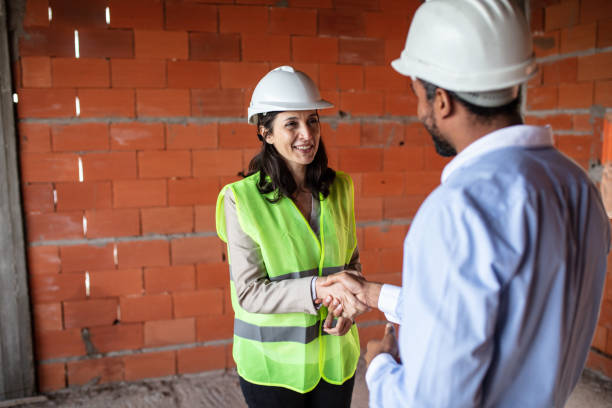 mujer arquitecta apretando de manos con un hombre de negocios en una obra de construcción - hardhat construction men handshake fotografías e imágenes de stock