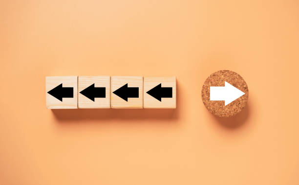 istock White arrow on circle wooden move on different direction with black arrow on cube for business and technology disruption concept. 1359999275