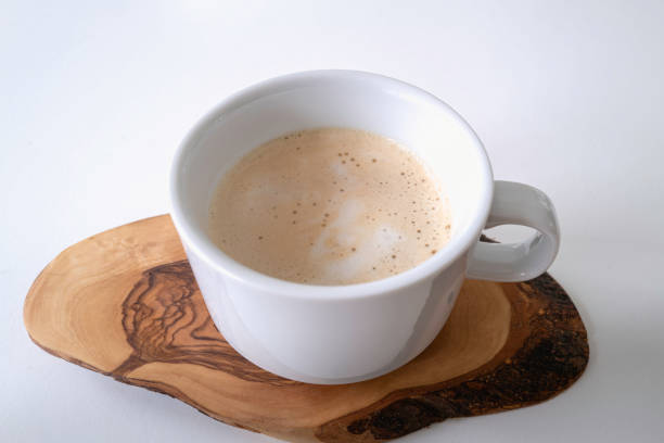 istock Latte with foam in a while cup served on a wooden coaster over the white table 1360001478