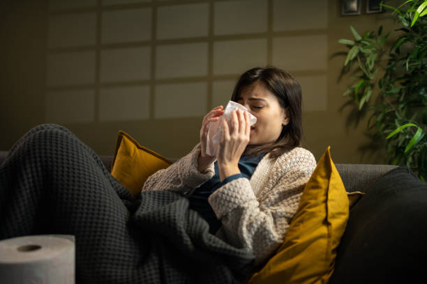 istock Woman blowing her nose while lying sick in bed 1360002920