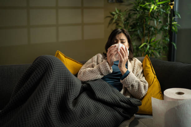 istock Woman blowing her nose while lying sick in bed 1360009212