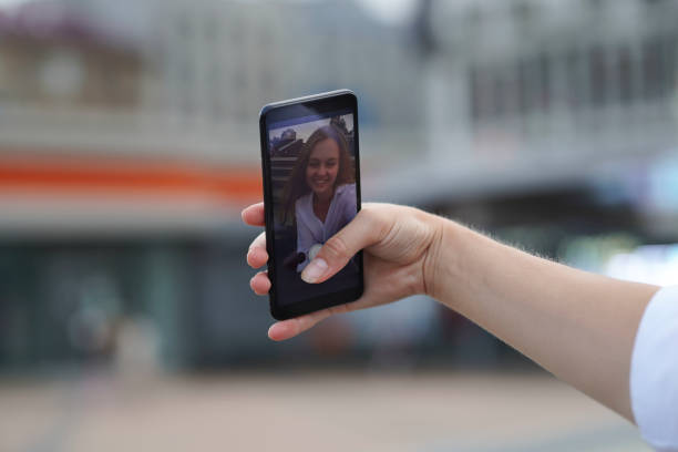 istock Attractive young blonde woman making selfie outdoors using smartphone at summer day. 1360011108