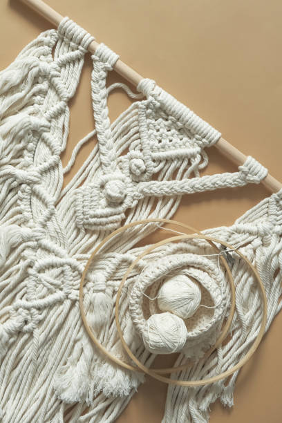 istock Macrame. Handmade macrame weaving and cotton threads on a rustic wooden stick. Scandinavian style in the interior, boho style. Cozy home recycling, zero waste,eco friendly, small business 1360011170