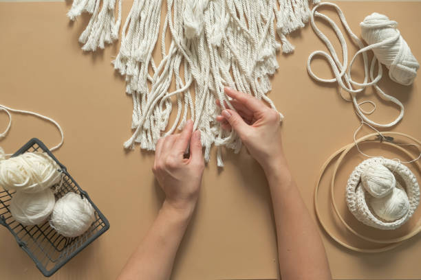 istock Macrame. Handmade macrame weaving and cotton threads on a rustic wooden stick. Scandinavian style in the interior, boho style. Cozy home recycling, zero waste,eco friendly, small business 1360011228