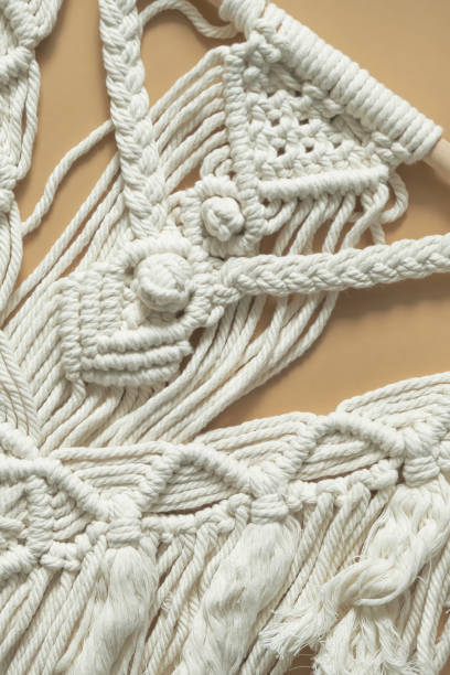 istock Macrame. Handmade macrame weaving and cotton threads on a rustic wooden stick. Scandinavian style in the interior, boho style. Cozy home recycling, zero waste,eco friendly, small business 1360011246
