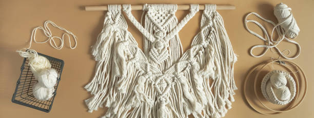 istock Macrame. Handmade macrame weaving and cotton threads on a rustic wooden stick. Scandinavian style in the interior, boho style. Cozy home recycling, zero waste,eco friendly, small business 1360011804