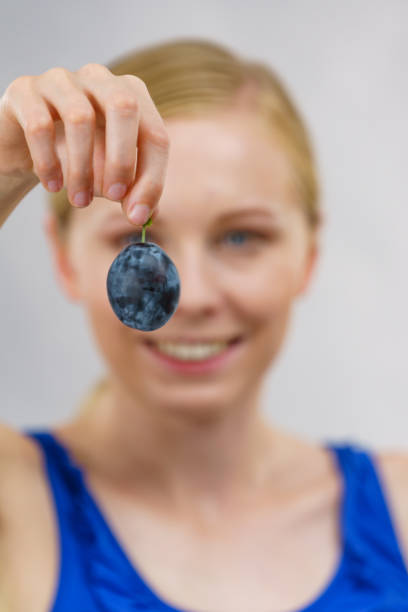 девушка держит плоды сливы - plum eating women fruit стоковые фото и изображения