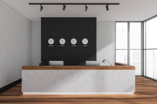 istock Reception interior desk with computers and clocks on the wall near window 1360011944